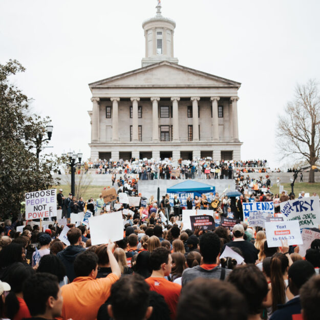 Crowd holding signs at a protest in front of the Tennessee Capitol