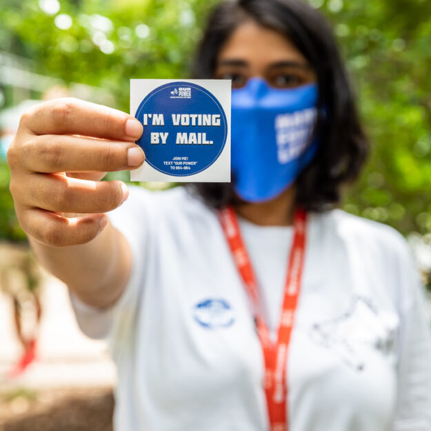 March For Our Lives member holds sticker saying, "I'm voting by mail."