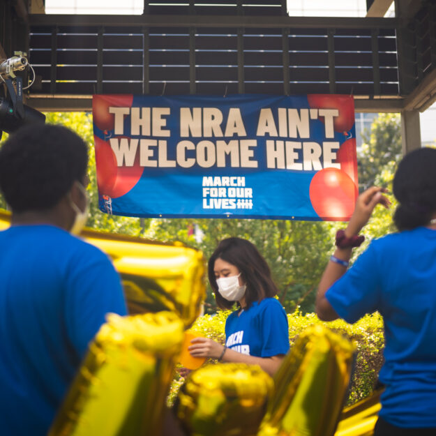 MFOL Houston host event with a banner saying, "THE NRA AIN'T WELCOME HERE" and gold balloons.